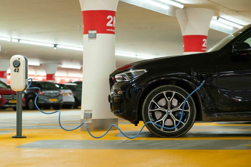 Une voiture électrique garée sur une place de stationnement, branchée à une borne de rechargement.